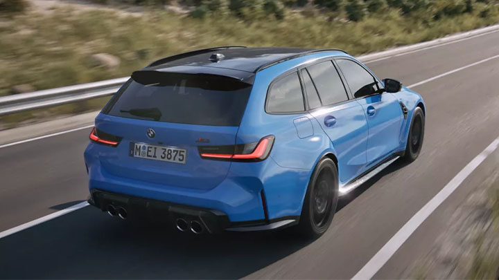 Stationary rear quarter shot of a driving blue BMW M3 Touring