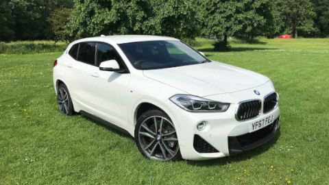 White BMW X2 Static Parked on a Grass Field with Trees in the Background