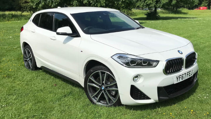White BMW X2 Static Parked on a Grass Field with Trees in the Background