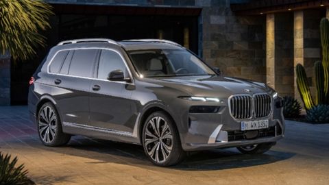 Dark silver BMW X7 parked in front of a modern house