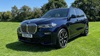 Blue BMW X7 M Sport Static in Grass Field in front of Trees