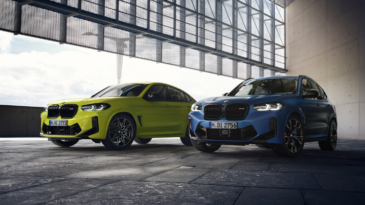 Two BMW cars parked in a warehouse. One is lime green and the other blue.