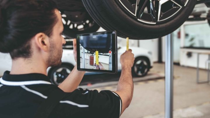 Man holding up an iPad to take photos of cars being serviced