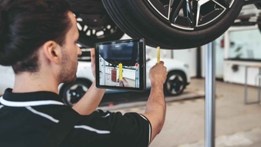 Man holding up an iPad to take photos of cars being serviced