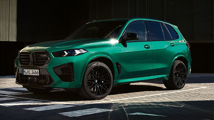 Green BMW X5 M driving on the street