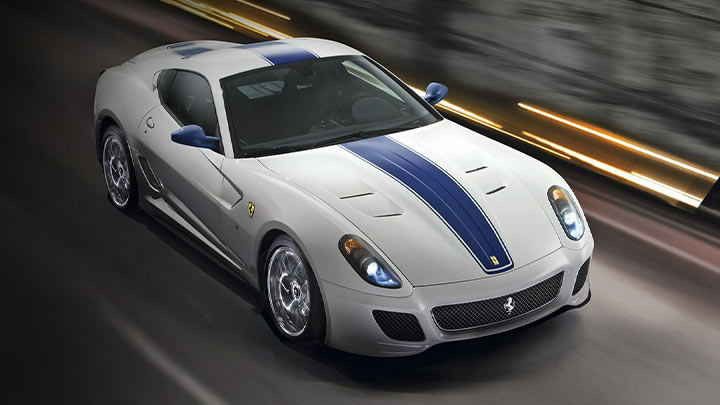White Ferrari 599 with a blue stripe driving at speed
