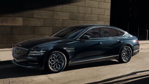 Blue Genesis G80 parked next to a large building