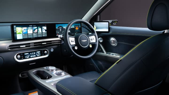 Genesis GV60 interior with black leather and a close up of the steering wheel and infotainment system