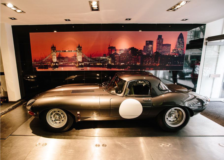 Jaguar Lightweight E-Type parked over the showroom elevator.