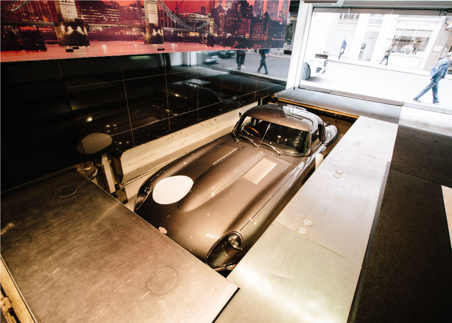 Lightweight E-Type goes down the elevator in the Mayfair showroom.