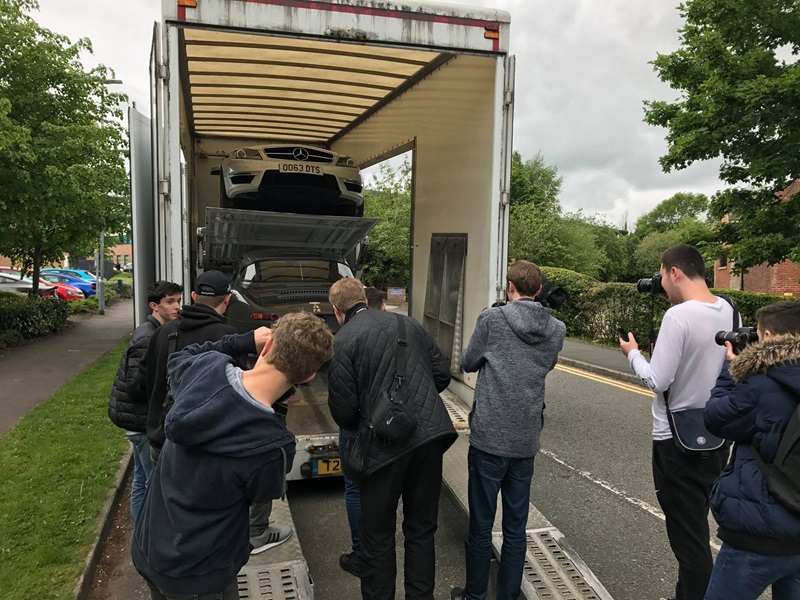 People taking pictures of the E-Type on the lorry.