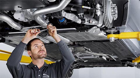 technician completing repair on exhaust system of jaguar