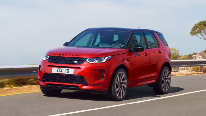 Land Rover Discovery Sport in red driving on the road.