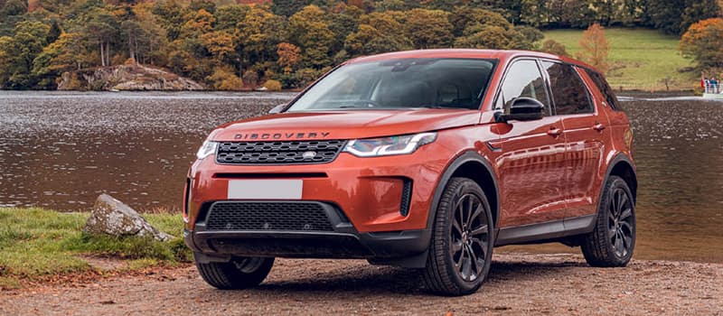 Orange Land Rover Discovery Sport, parked next to river