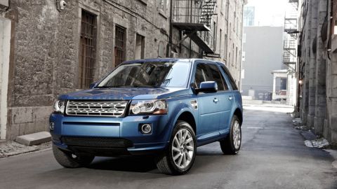 Blue Land Rover Freelander parked in an alley with houses made of stone