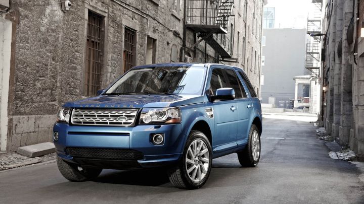 Blue Land Rover Freelander parked in an alley with houses made of stone