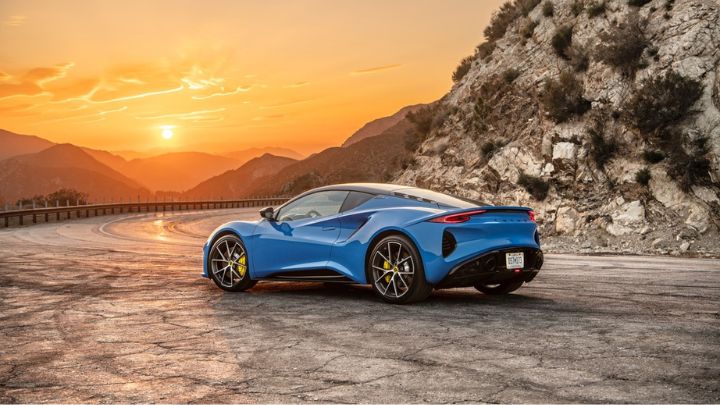 Blue Lotus Emira parked in the mountains with a beautiful sunset in the background