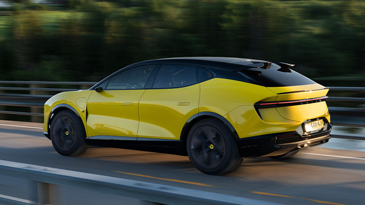 Side quarter shot of a driving yellow Lotus Eletre