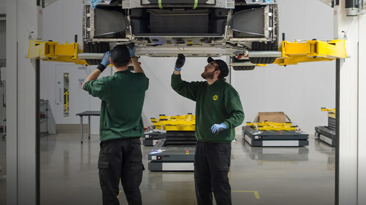 Two Lotus technicians working on the underside of a Lotus