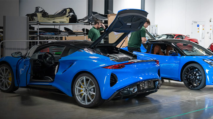 Two blue Lotus Emiras parked in a workshop for a service