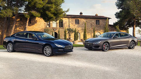 Two Maserati models parked outside a countryside home