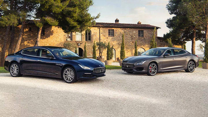 Two Maserati models parked outside a countryside home