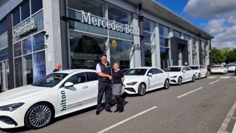 A man and a woman shaking hands in front of a Stratstone Mercedes-Benz retailer