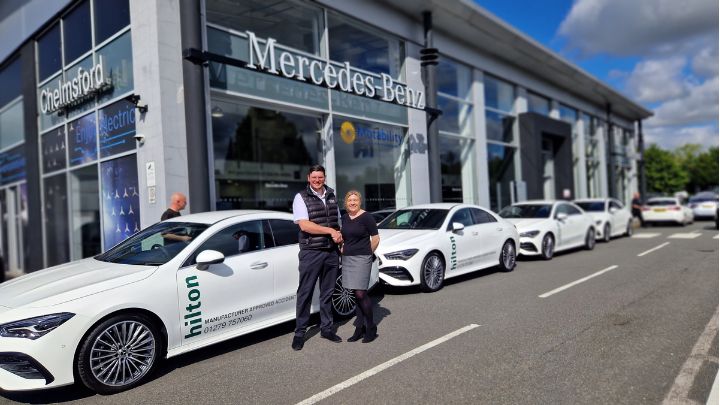 A man and a woman shaking hands in front of a Stratstone Mercedes-Benz retailer