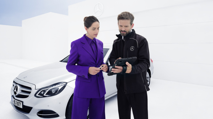 Two People With a Tablet Chatting In Front Of White Mercedes Vehicle