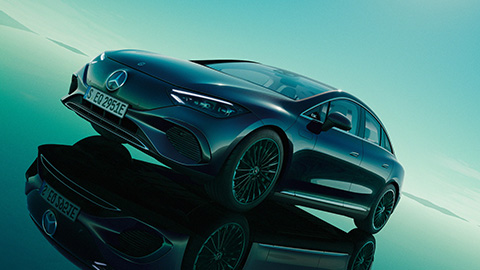 Black Mercedes-Benz EQE driving on a green background