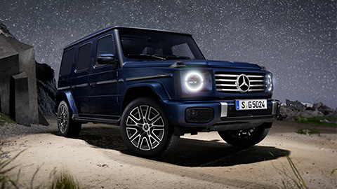 Navy blue Mercedes-Benz G-Class parked in front of a cave with a stary sky in the background
