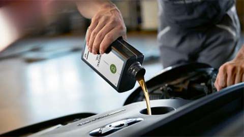 technician refilling engine oil on mini