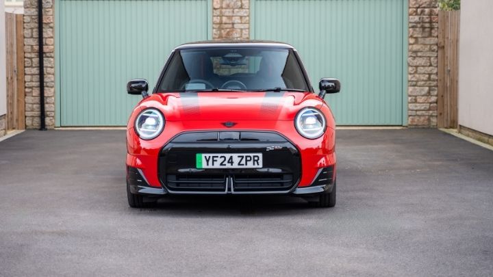 Red MINI parked in front of a couple of green garage doors