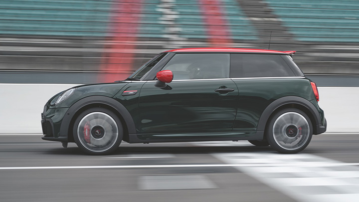 Green MINI Hatch John Cooper Works, side shot, driving on track