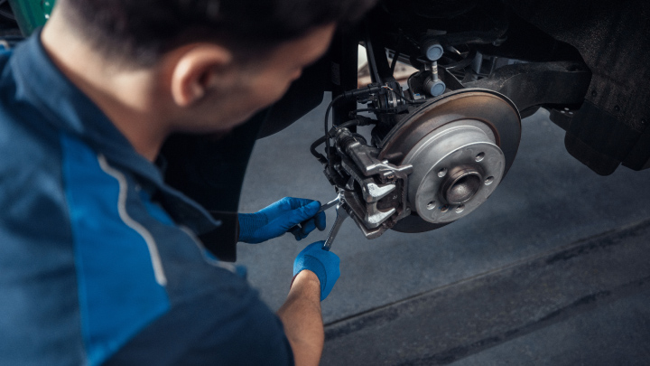 Over the shoulder of a mechanic working on a wheel