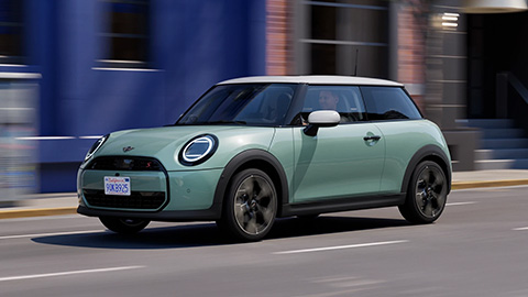 Green MINI Cooper driving on the road