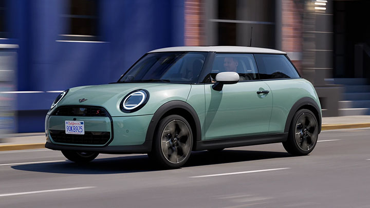 Green MINI Cooper driving on the road
