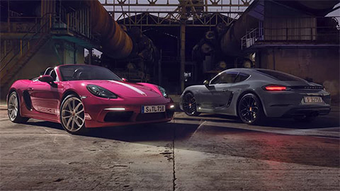 Pink Porsche 718 Boxster parked next to a grey Porsche 718 Cayman in an industrial estate