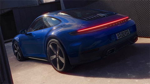 Rear shot of a blue Porsche 911 parked in the entrance to a compound