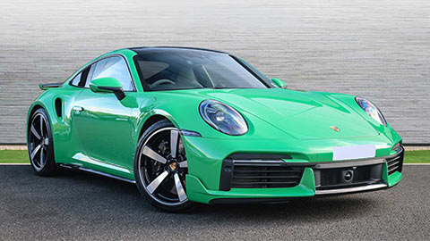 Green Porsche 911 Turbo S parked in front of a grey background