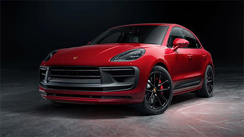 Red Porsche Macan parked in a black studio with a marble effect floor
