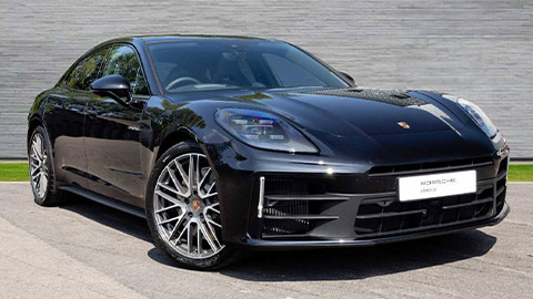 Black Porsche Panamera Turbo 4 e-Hybrid parked in front of a grey background