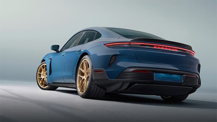 Blue Porsche Taycan parked in a studio with a grey and blue background