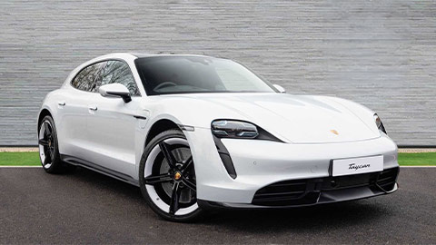 White Porsche Taycan Sport Turismo parked in front of a grey background