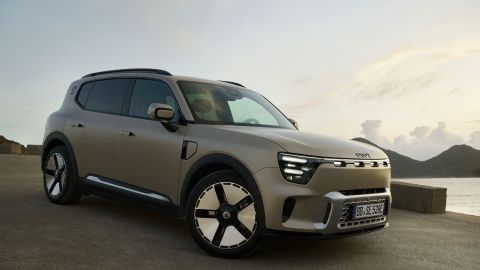 Grey smart #5 parked in by the ocean with clouds in the background