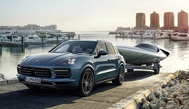 Blue 3rd Generation Porsche Cayenne towing a boat.